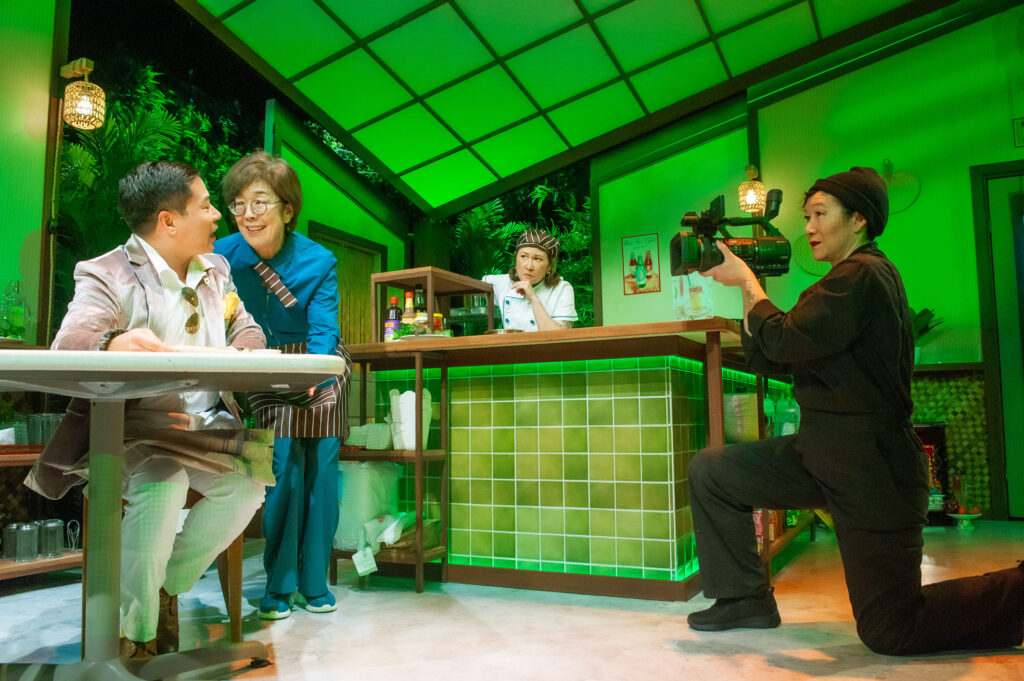 L-R) A food critic (Will Dao) samples cuisine, watched by Lan (Sharon Omi), Mai (Jenny Nguyen Nelson) and a camera person (Erin Mei-Ling Stuart) in San Francisco Playhouse's World Premiere Play "My Home on the Moon," performing January 25 - February 24.