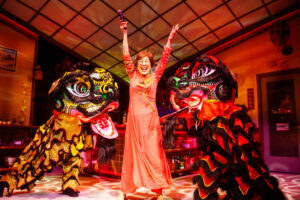 Lan (Sharon Omi - center) celebrates the new year with lion dancers (left - Erin Mei-Ling Stuart, right- Will Dao). SF Playhouse photo by Jessica Palopoli.